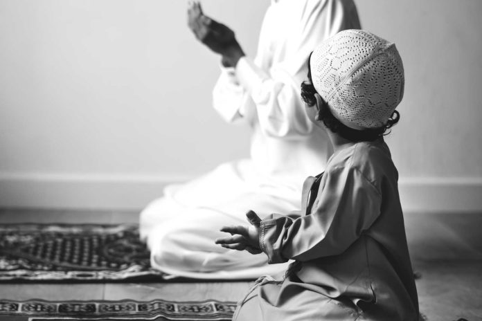 Muslim boy learning how to make Dua to Allah
