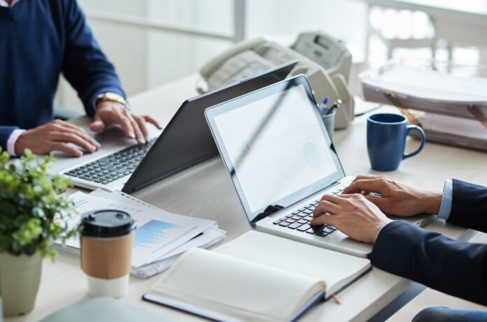 Cropped image of business people working on laptops in office
